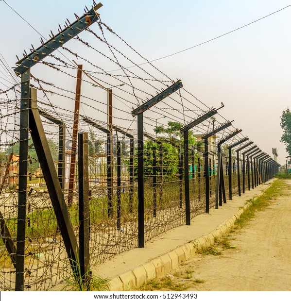 The border wired fences in India with a blur\
background of surroundings
