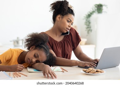 Bored African American Teen Girl Sitting By Her Working Mom, Busy Black Lady Having Phone Conversation And Typing On Laptop, Upset Daughter Laying On Table, Looking For Mother Attention, Copy Space
