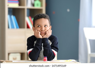 Bored African-American boy sitting at table in room - Powered by Shutterstock