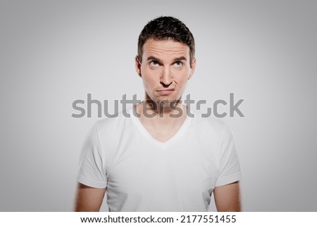 bored and annoyed face expression of man while look at camera and show his inner feelings and emotion with eyes and glimpse isolated on gray background