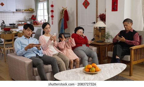 bored asian extended family ignoring each other while spending time on mobile phones. vr games and tv during Chinese new year in the living room at home - Powered by Shutterstock