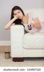 Bored Asian Girl Lying On The Sofa Watching Tv At Home In The Sitting Room