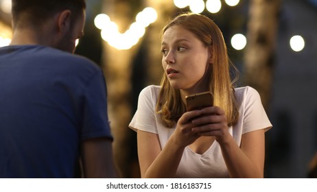 Bored Beautiful Young Woman On Bad Date Using Her Phone.