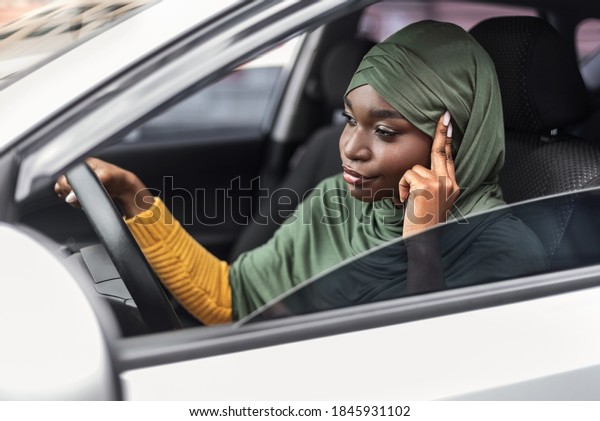 Bored Black Muslim Woman In Hijab Driving Car,\
Stuck In Traffic Jam, Sitting On Driver\'s Seat Holding Steering\
Wheel And Looking On The Road, Annoyed Lady In Headscarf Waiting\
Long Time To Drive