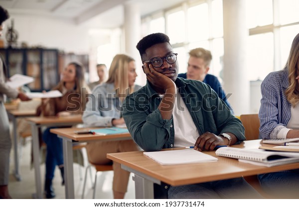 Bored black student sitting at university\
classroom and thinking of something.\
