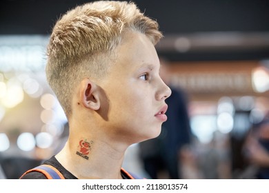 Bored Blond-haired Teenage Boy With Serious Face Expression Sits In Airport Waiting Hall Against Blurred Crowd Extreme Closeup