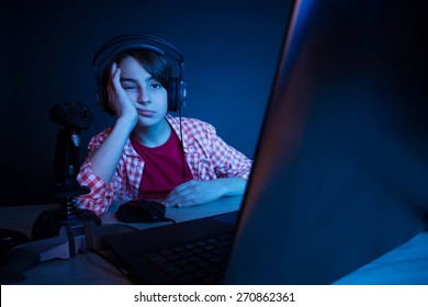 Bored boy. He want ot sleep after video games played all night long. In blue light of display emotional kid play computer games online. - Shutterstock ID 270862361