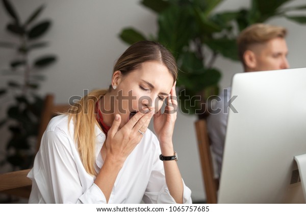 Bored businesswoman yawning at workplace feeling
no motivation or lack of sleep tired of boring office routine,
exhausted restless employee gaping suffering from chronic fatigue
or overwork concept