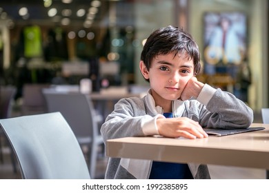 Bored Child Waits At A Restaurant Table In A Shopping Mall