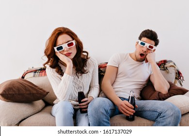 Bored Couple Drinking Soda On Couch. Indoor Shot Of Woman And Man Watching 3d Film.