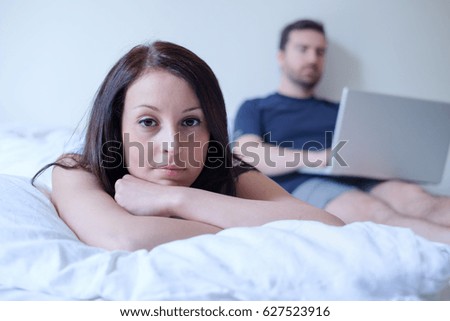Bored couple lying in the bed , man is neglecting his girlfriend internet