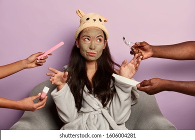 Bored Dissatisfied Woman Refuses All Beauty Treatments, Discontent With Care In Spa Salon, Applies Clay Mask On Face For Rejuvenation, Wears Soft Bath Hat And Robe, Isolated Over Purple Wall