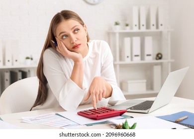 Bored female accountant with calculator working in office