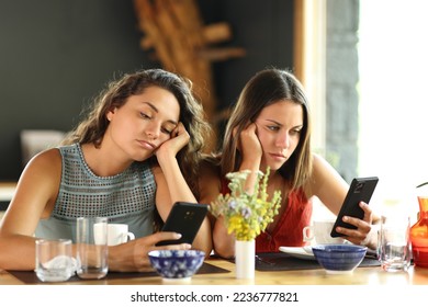 Bored friends checking smart phones in a restaurant - Shutterstock ID 2236777821