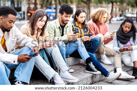 Bored friends group using mobile smart phone sitting at university college yard - Young people addicted by smartphone devices - Technology concept with always connected students on bright vivid filter