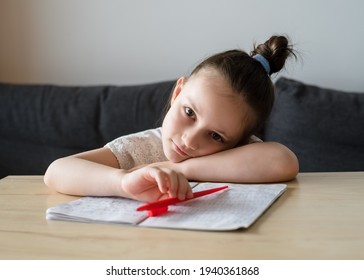 Bored Girl Child At Home Schooling. The Girl Studies At Home, The Concept Of Home Education And Preparation For The 1st Grade Of School. Close-up