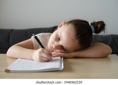 Bored Girl Child At Home Schooling. The Girl Studies At Home, The Concept Of Home Education And Preparation For The 1st Grade Of School. Close-up