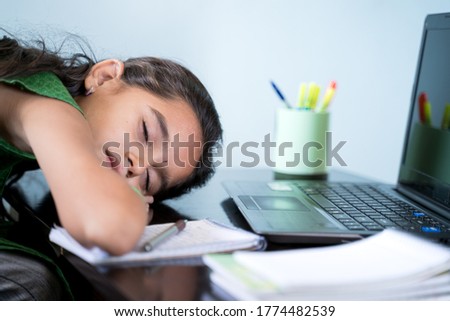 Bored Girl child slept infront of laptop - concept of kid tired from e-learning or online education at home during covid-19 or coronavirus outbreak