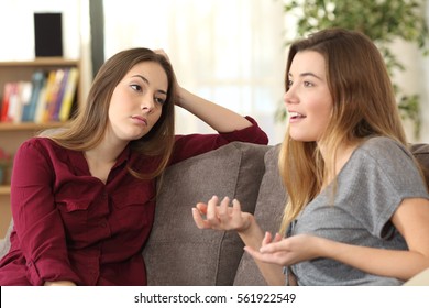 Bored girl listening to her friend having a conversation sitting on a couch in the living room at home - Powered by Shutterstock