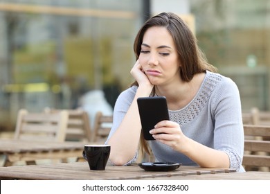 Bored Girl Looking Disappointed At Her Smart Phone On A Cafe Terrace