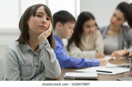 Bored Girl Sitting At Lesson In Classroom Not Paying Attention To Teacher And Classmates