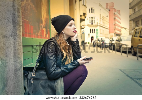 Bored girl\
sitting on the ground listening to\
music