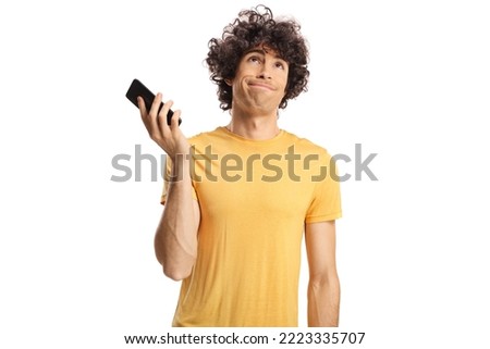Bored guy listening to phone conversation on speakerphone and holding his phone away isolated on white background