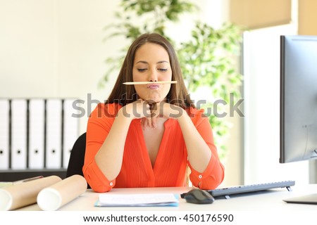 Bored or incompetent businesswoman playing with a pencil in a desktop at office