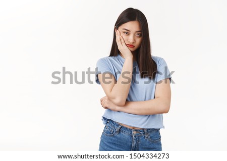 Bored indifferent asian teenage girl unwilling take part family event lean palm cheek look reluctant bothered uninterested express lack interest attend boring meeting standing white background sad