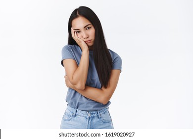 Bored and indifferent upset asian female, facepalm, look bothered and unamused, stare camera displeased, dying from boredom, jealous everyone partying while being grounded, white background