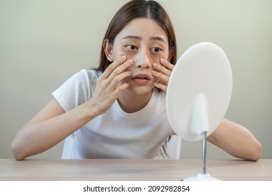 Bored, insomnia asian young woman, girl looking at mirror, without makeup, touch under eyes with problem of dark circles, puffiness, swollen or wrinkles on face. Sleepless, sleepy people, copy space