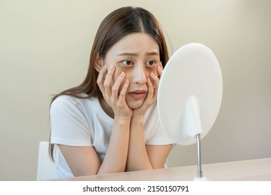 Bored, insomnia asian young woman, girl looking at mirror, without makeup, touch under eyes with problem of dark circles, puffiness, swollen or wrinkles on face. Sleepless, sleepy people, copy space - Shutterstock ID 2150150791