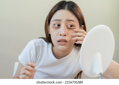 Bored, insomnia asian young woman, girl looking at mirror, without makeup, touch under eyes with problem of dark circles, puffiness, swollen or wrinkles on face. Sleepless, sleepy people, copy space - Shutterstock ID 2156735389