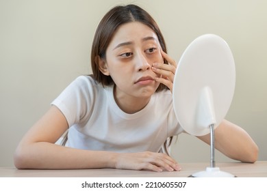 Bored, insomnia asian young woman, girl looking at mirror hand touching under eyes with problem of black circles or panda puffy, swollen and wrinkle on face. Sleepless, sleepy healthcare person. - Shutterstock ID 2210605507