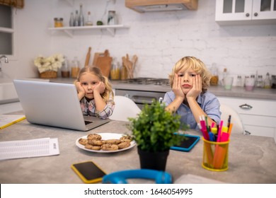 Bored Kids. Two Kids Sitting At The Table And Looking Bored