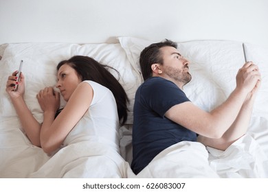 Bored Lovers Couple In Bed And Using  Mobile Phone 