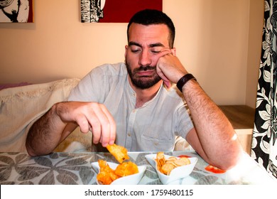 Bored Man Eating Snacks In The Living Room.