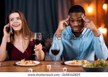 Bored Man Sitting At Date Next To His Girfriend Talking On Cellphone