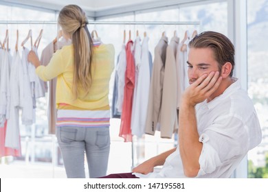 Bored Man While His Girlfriend Is Shopping In A Boutique