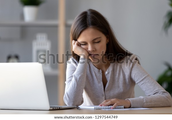 Bored at office work funny sleepy woman worker\
resting on hand sleeping at workplace, unmotivated lazy teen\
student feeling drowsy falling asleep near laptop, boring job and\
lack of sleep concept