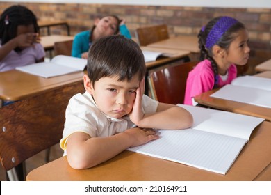 Bored pupil sitting at his desk at the elementary school - Powered by Shutterstock