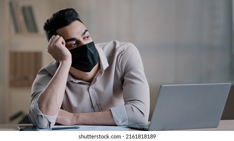 Bored Sad Hispanic Worker Young Business Man In Medical Mask Tired Unmotivated Employee Disinterested In Dull Distant Work On Computer Lazy Male Arab Guy Feeling Lack Of Motivation Boredom In Office