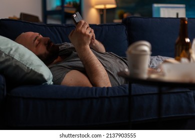 Bored Sad Person With Chronic Depression Using Smartphone To Browse Internet And Text On Social Media. Anxious Lonely Man Suffering From Mental Health Illness, Having Mobile Phone.