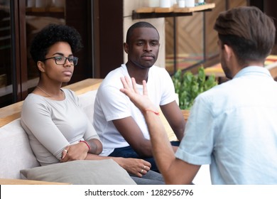 Bored Serious Black Married Couple Sitting Together On Couch Visiting Medical Specialist Listening Psychologists Counselor Feeling Disinterested And Mistrust To Methods Of Psychological Assistance