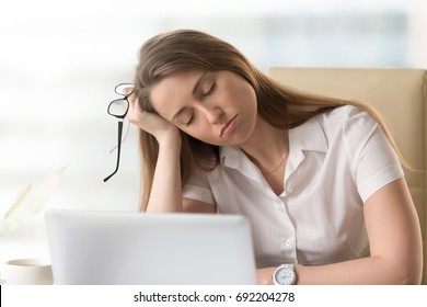 Bored sleepy businesswoman sitting half asleep at workplace, lazy woman disinterested in boring routine, tired employee dozing on hand during break, falling asleep at desk, lack of sleep, head shot