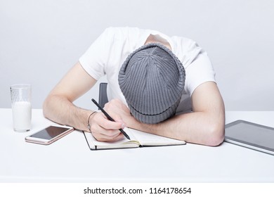 Bored Sleepy Male Office Manager In Hat Works Late At Night, Taking Nap On Table, Another Cup Of Strong Take Away Coffee Does Not Help Not To Fall Asleep. People, Job, Tiresome And Overwork Concept.