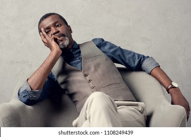 bored stylish african american man in waistcoat sitting in armchair - Powered by Shutterstock