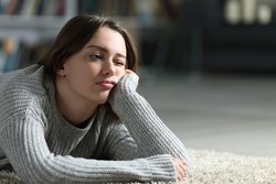 Bored Teen Looking Away Lying On The Floor At Home