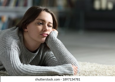 Bored teen looking away lying on the floor at home
