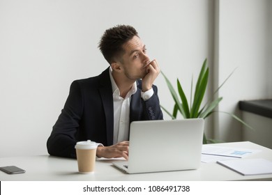 Bored Tired Millennial Businessman In Suit Feeling Dull Working On Laptop At Workplace, Absent-minded Employee Thinking Or Boring Monotonous Office Routine, No Motivation And Lack Of Ideas Concept